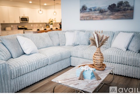 A living room with a grey couch and a coffee table with a plant and a gift box on it.