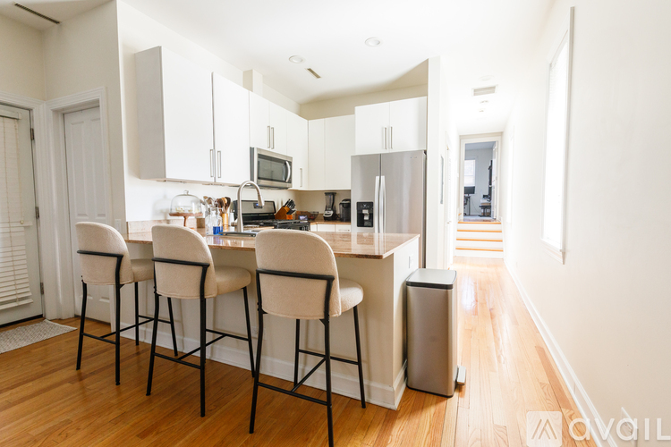 A kitchen with white cabinets and a bar area with four chairs.