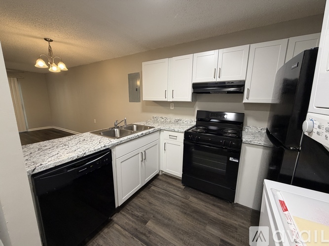 A kitchen with black appliances and white cabinets.