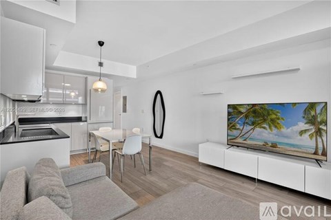 A modern living room with a grey sofa and a television displaying a beach scene.