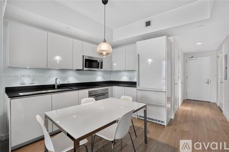 A modern kitchen with white cabinets and a dining table.