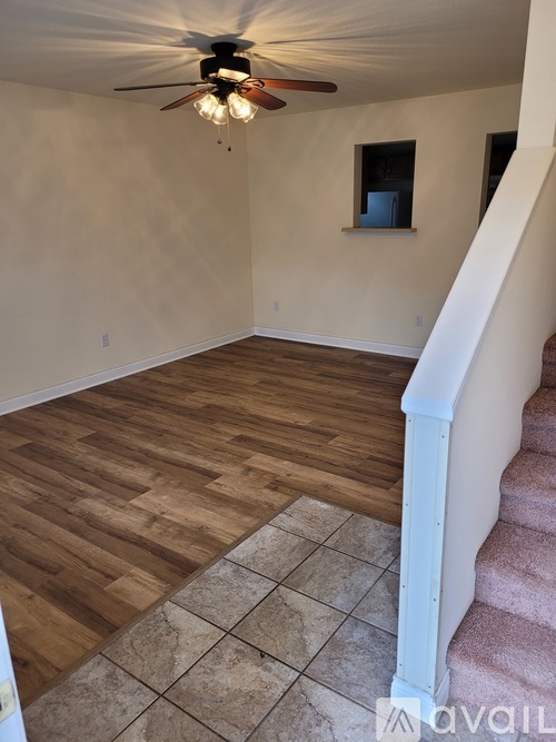 A room with a ceiling fan and a staircase.