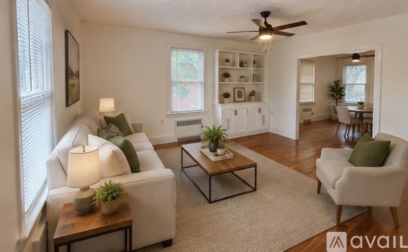 A living room with a white couch, a coffee table, and a ceiling fan.