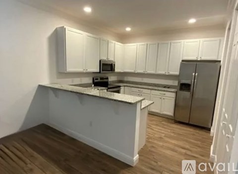 A kitchen with white cabinets and a wooden island.