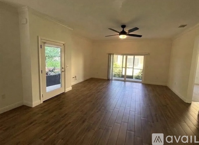 A spacious room with wooden flooring and a ceiling fan.
