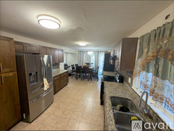 A kitchen with a refrigerator, sink, and dining table.