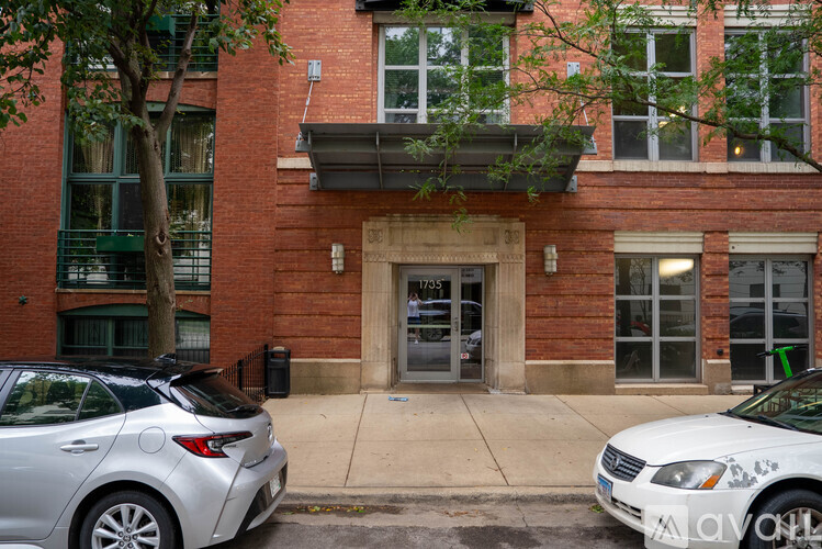 A silver car is parked in front of a brick building.