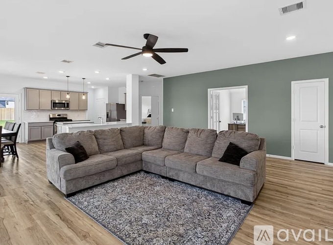 A living room with a grey sectional sofa and a rug in front of it.