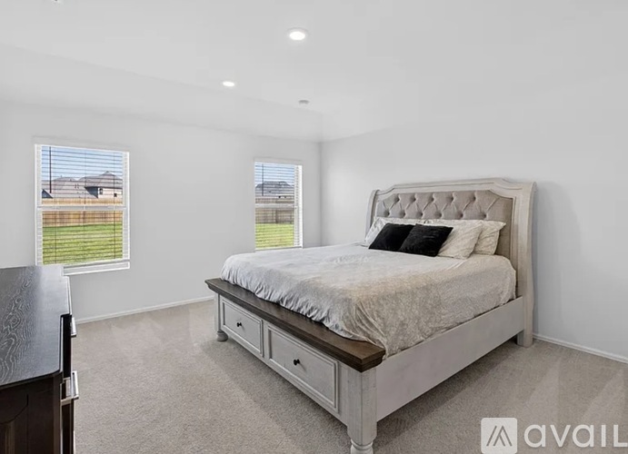 A bedroom with a large bed and a window overlooking a fence.