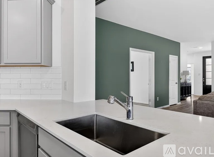 A modern kitchen with a black sink and grey cabinets.