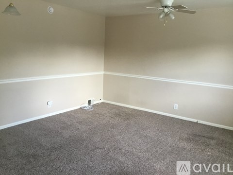 A room with a carpeted floor and a ceiling fan.