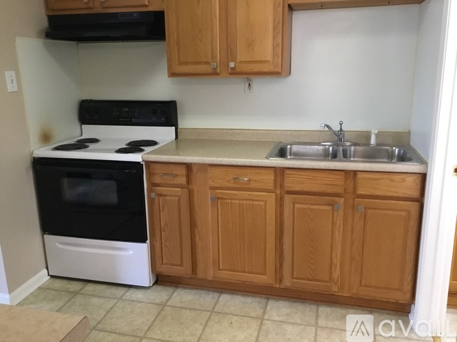 A kitchen with a white stove and wooden cabinets.