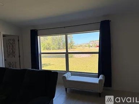 A living room with a black couch and a white chair in front of a large window.