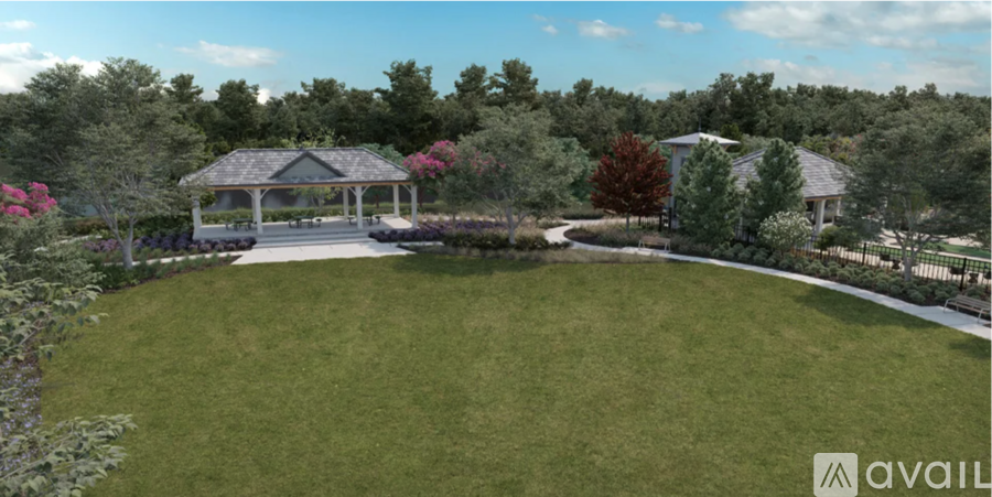 A gazebo is surrounded by a well-manicured lawn and trees.