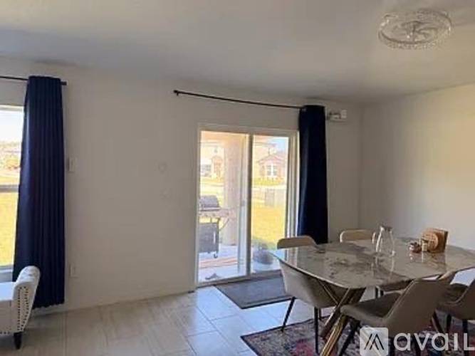 A dining room with a table and chairs and a sliding glass door.