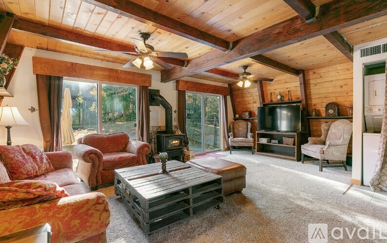 A living room with a wood-paneled ceiling and a large window.
