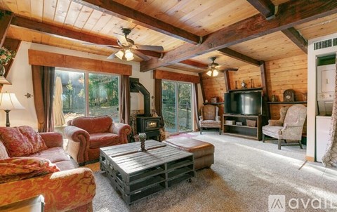 A living room with a wood-paneled ceiling and a large window.
