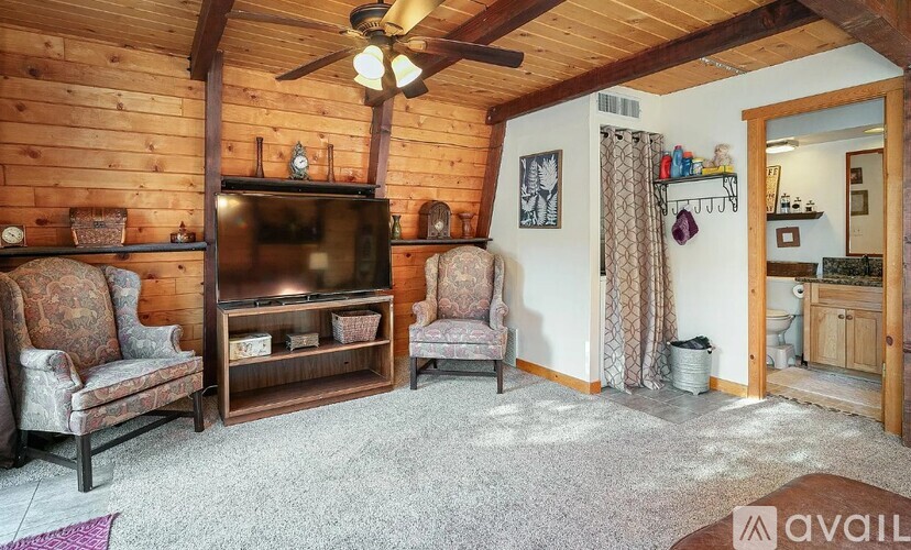 A living room with a wooden ceiling and a television.