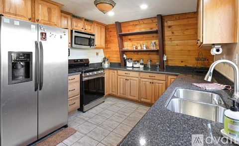 A kitchen with a refrigerator, microwave, oven, sink and cabinets.
