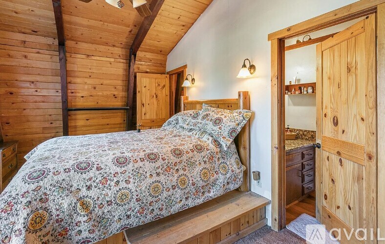 A bedroom with a bed and a wooden dresser.
