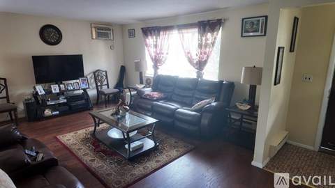 A living room with a leather couch, a coffee table, and a flat screen TV.