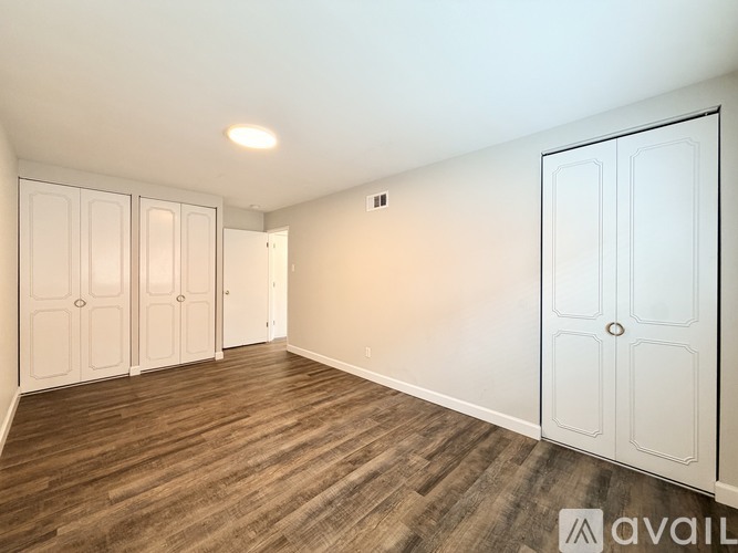 A room with white doors and wooden flooring is available for rent.
