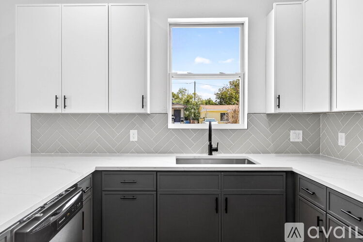 A kitchen with white cabinets and a window overlooking a landscape.
