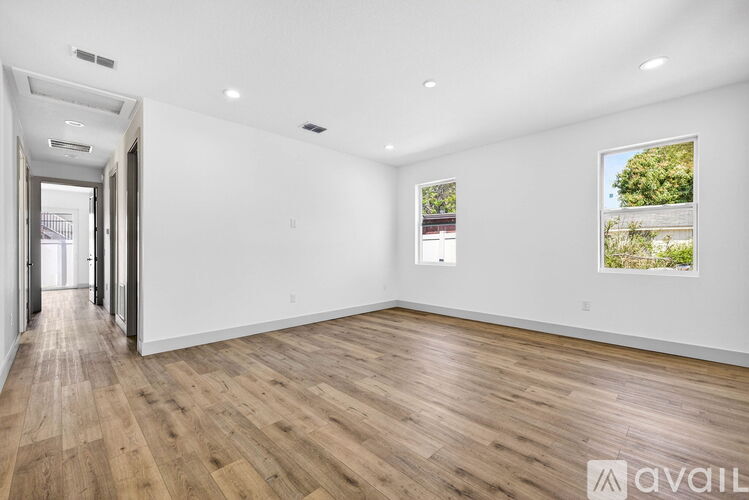 A spacious room with wooden flooring and white walls.