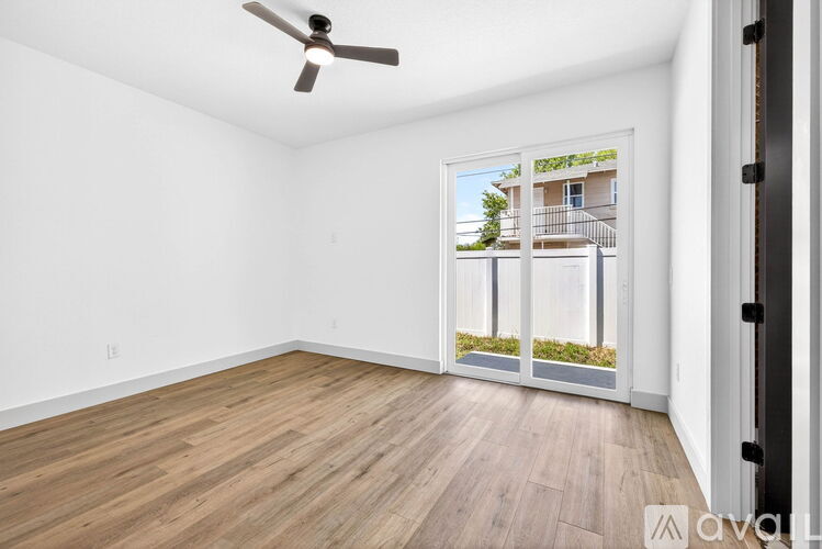 A room with a ceiling fan and a view of a building outside the window.