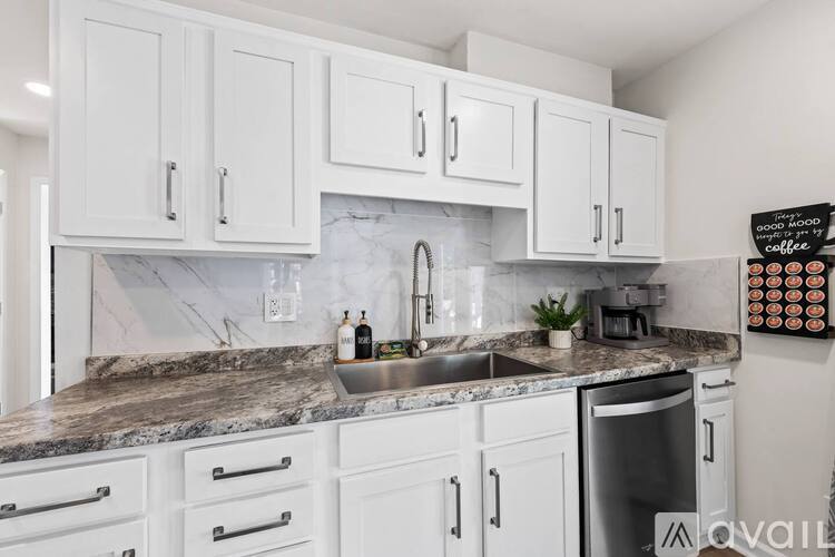 A kitchen with white cabinets and a marble countertop.