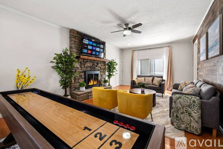 A pool table with the numbers 1, 2, and 3 on it is in the foreground of a room with a fireplace and a TV above it.