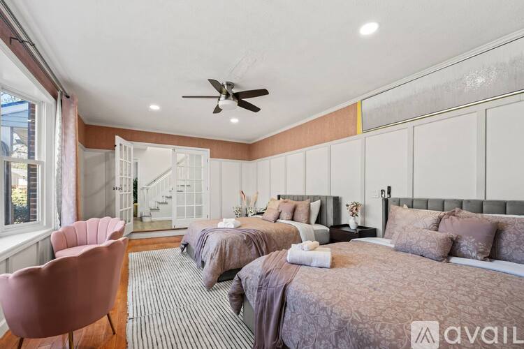 A bedroom with two beds and a pink chair.