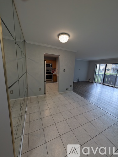 A spacious room with tiled flooring and a sliding glass door leading to a balcony.