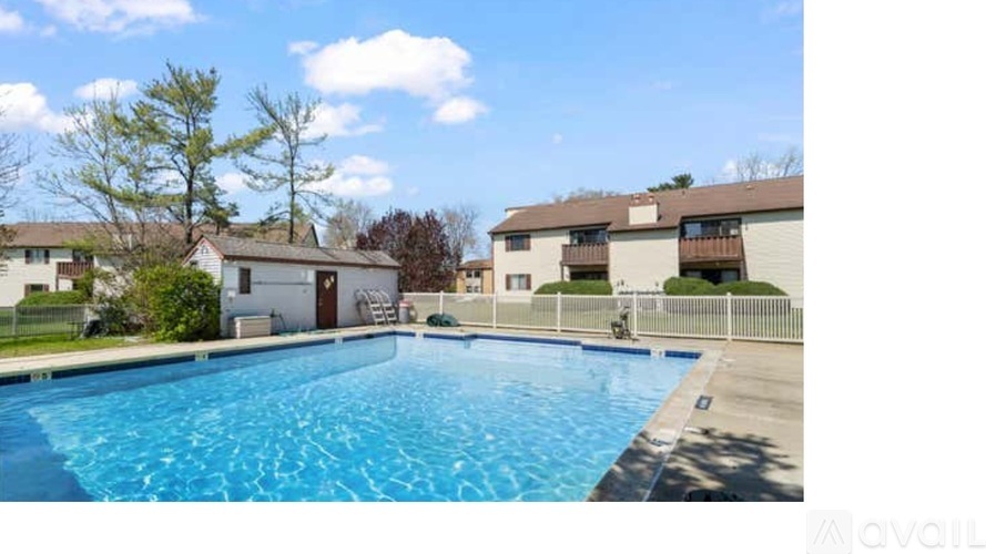 A swimming pool in a residential area with houses and trees in the background.