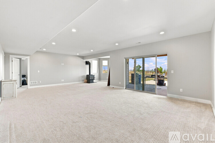 A spacious room with a carpeted floor and a large window.