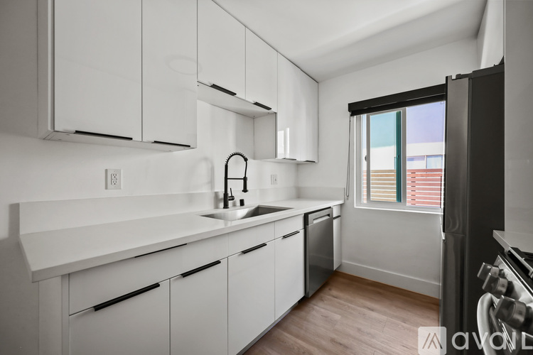 A kitchen with white cabinets and a black refrigerator.