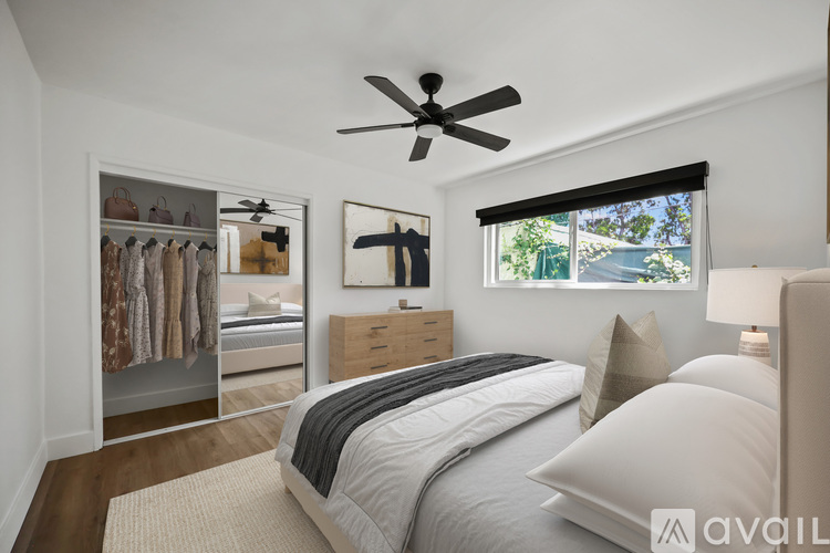 A bedroom with a large bed and a ceiling fan.