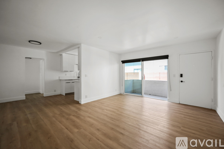 A spacious room with wooden flooring and white walls.