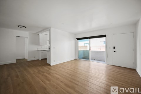 A spacious room with wooden flooring and white walls.