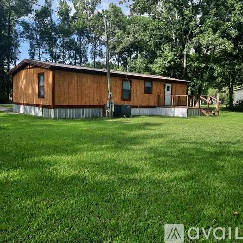 A wooden house with a metal base is surrounded by a grassy field.
