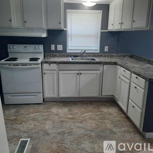 A kitchen with white cabinets and a granite countertop.