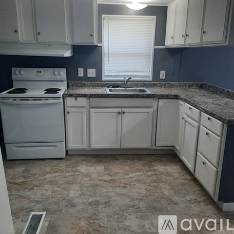 A kitchen with white cabinets and a granite countertop.