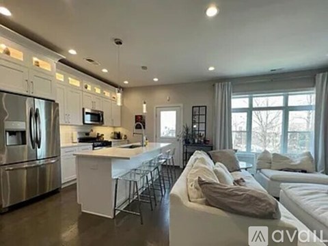 A modern kitchen with a refrigerator, microwave, and oven, and a living room with a couch and a coffee table.