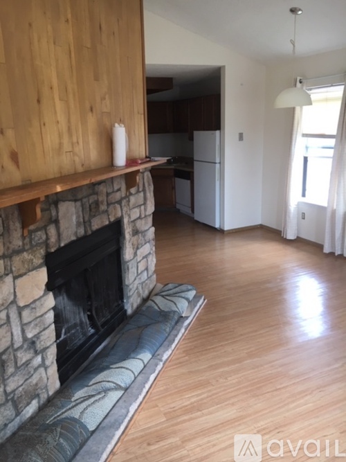 A living room with a stone fireplace and wooden walls.