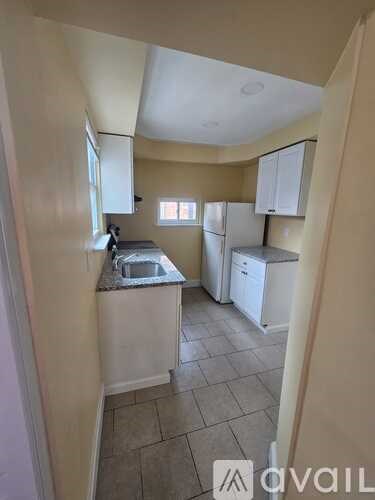 A kitchen with a sink, refrigerator, and cabinets.