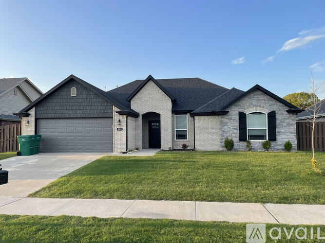 A house with a black roof and a grey garage door is for sale.