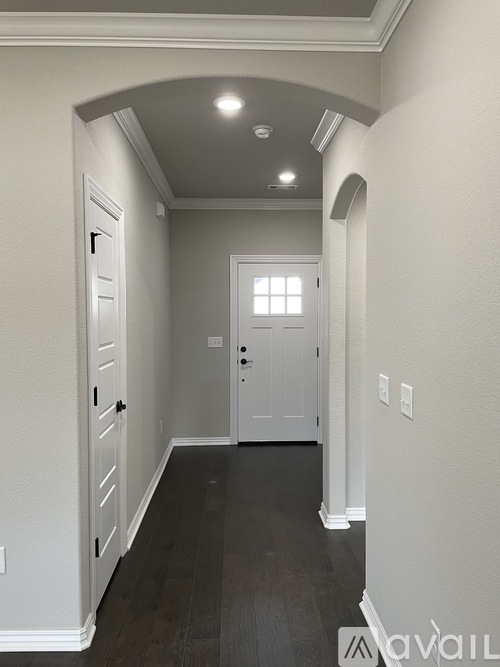 A hallway with a white door and a window.