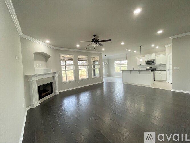A spacious living room with a fireplace and a ceiling fan.