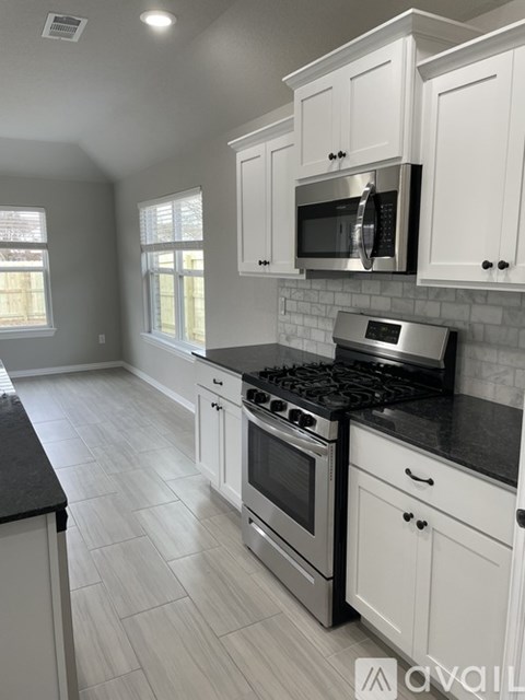 A kitchen with white cabinets and black countertops.