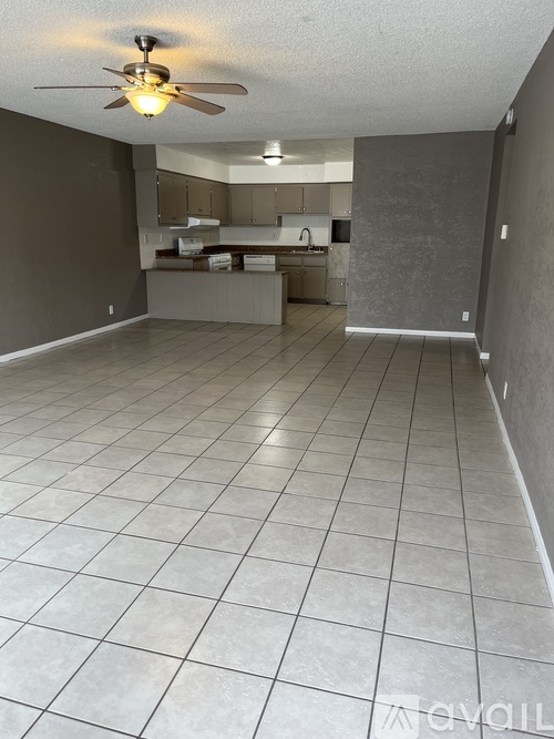 A spacious room with a ceiling fan and tiled flooring.